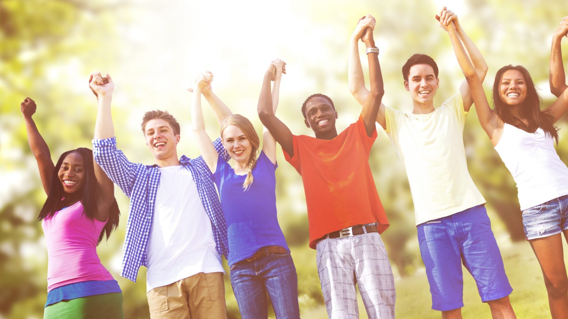 Group of youth holding hands, cheering, in forest setting