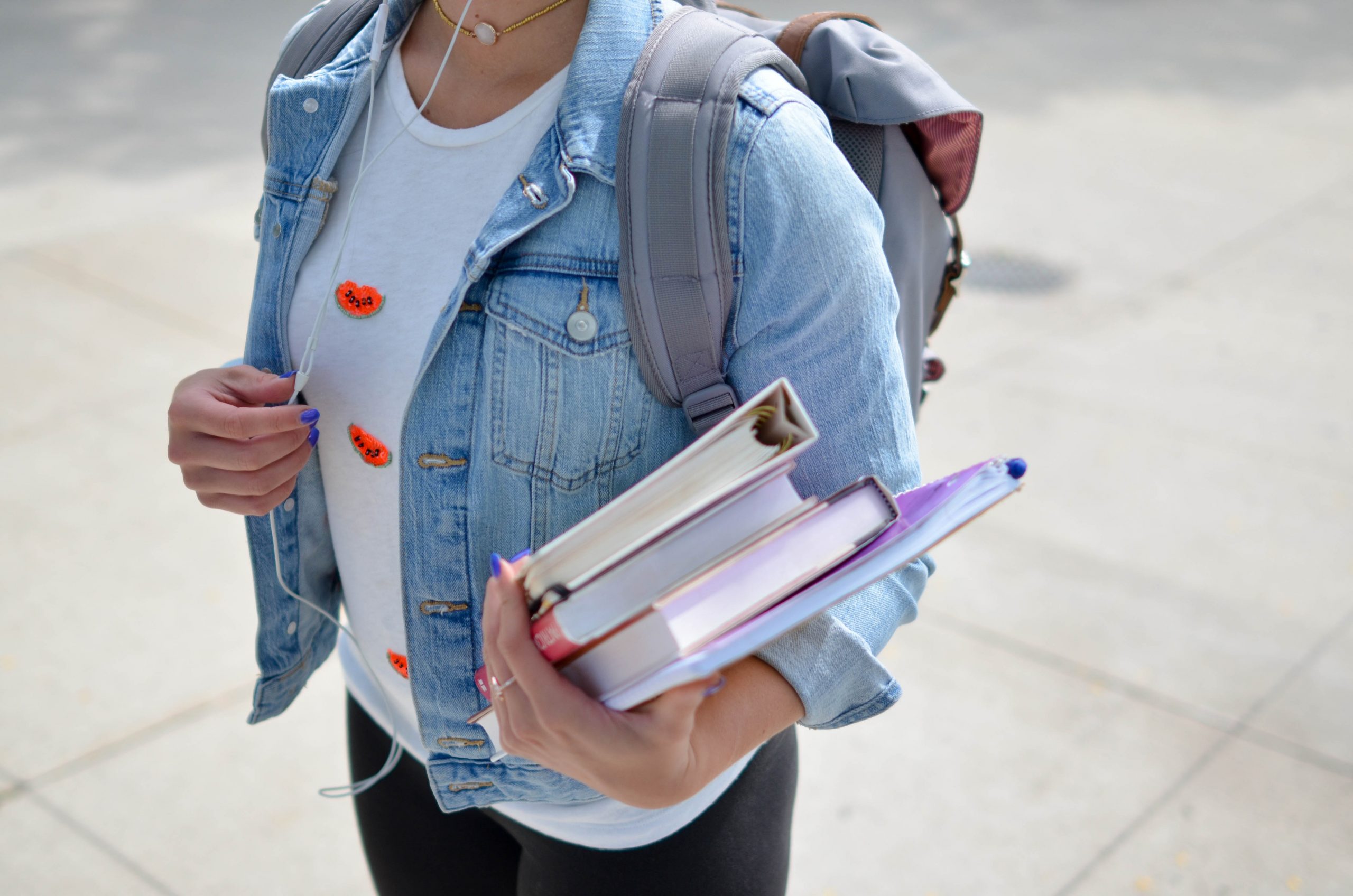 woman wearing blue denim jacket holding books