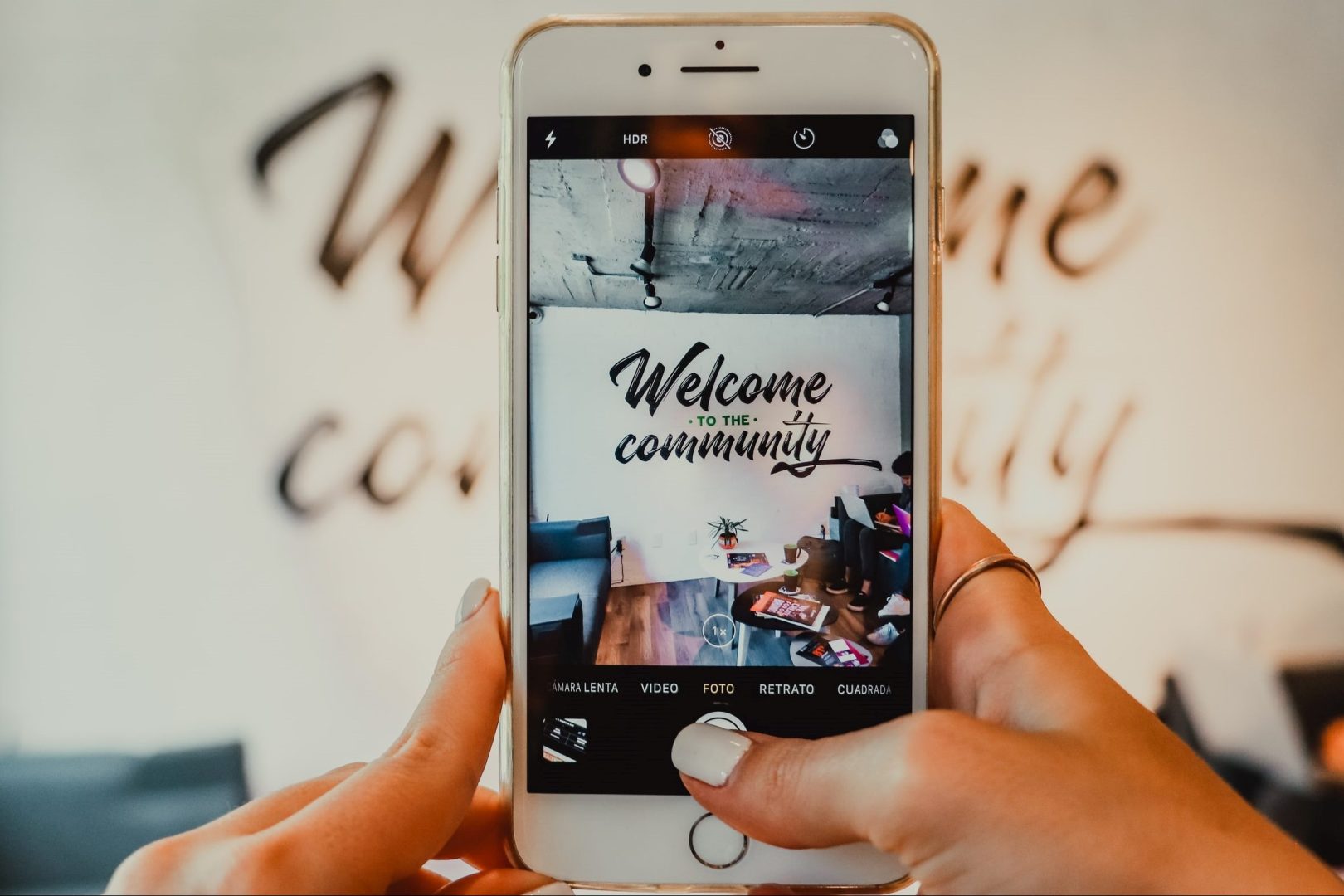 Image of person holding phone taking a picture of a sign that says Welcome to the Community