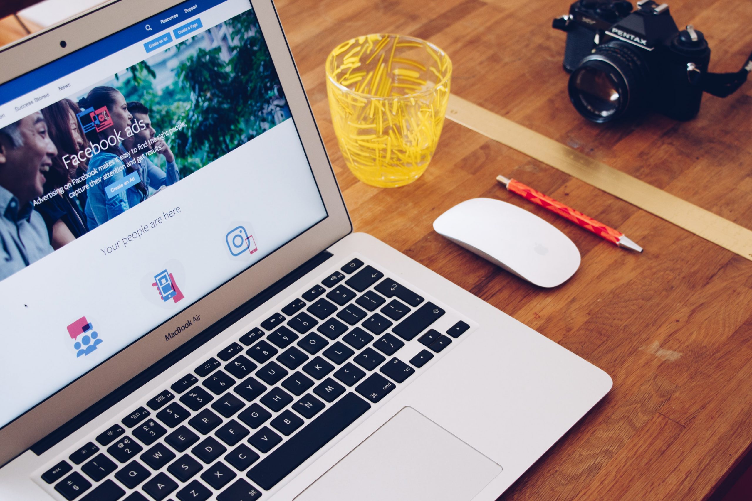 macbook air sitting on a wooden table with Facebook Ads on screen