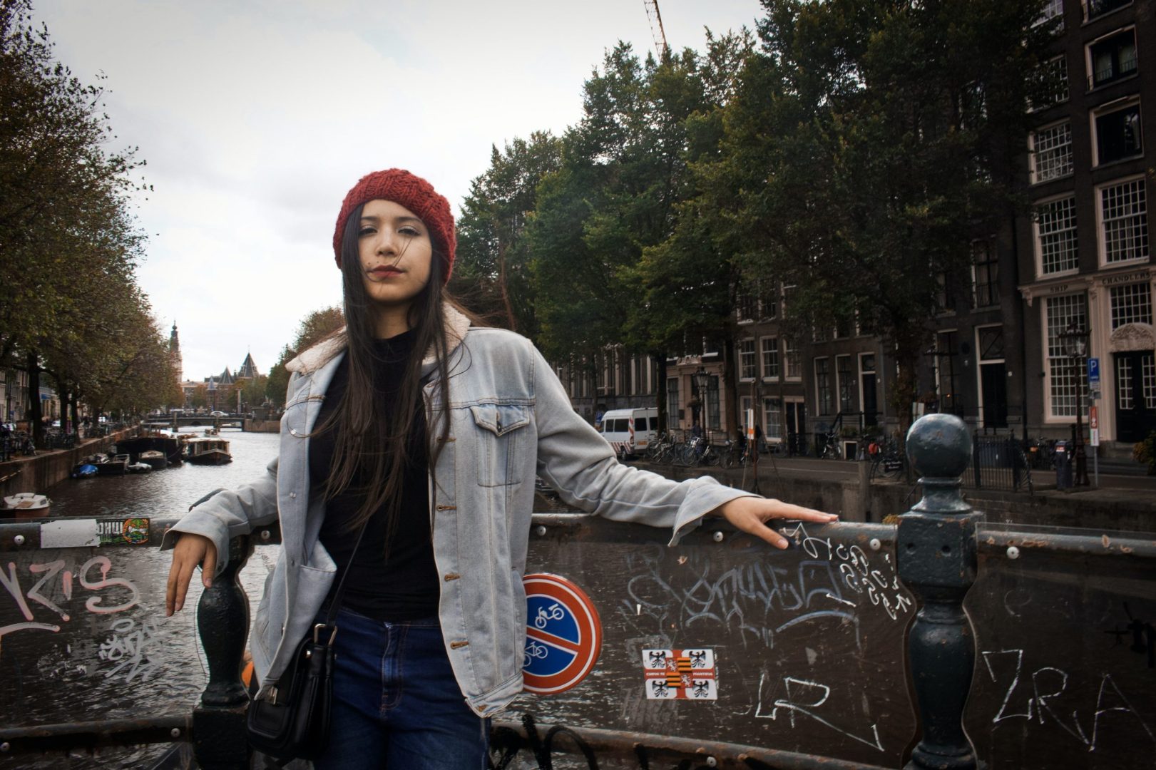 Women leans against railing overlooking a canal in Amsterdam.