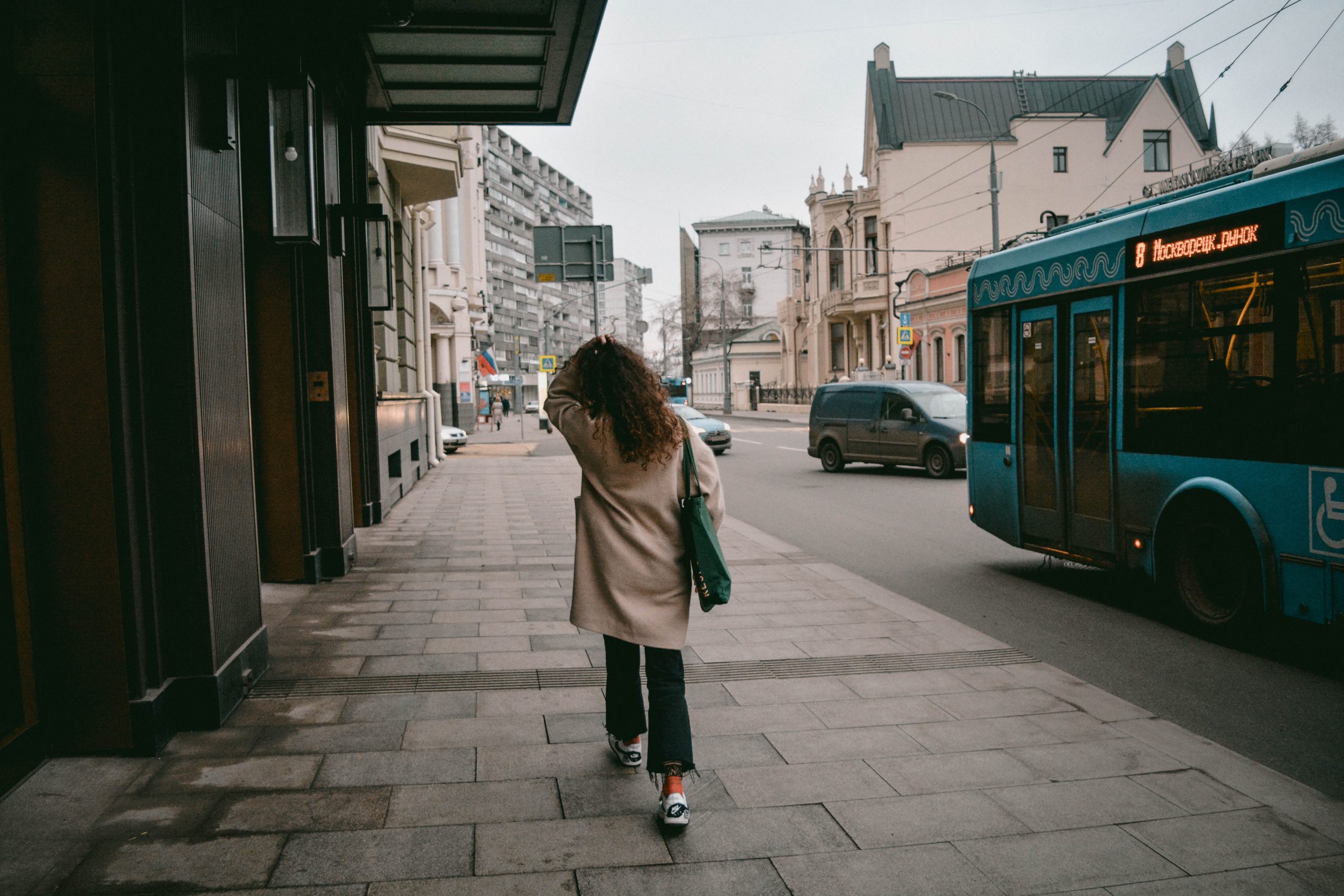 Woman walks next to a bus