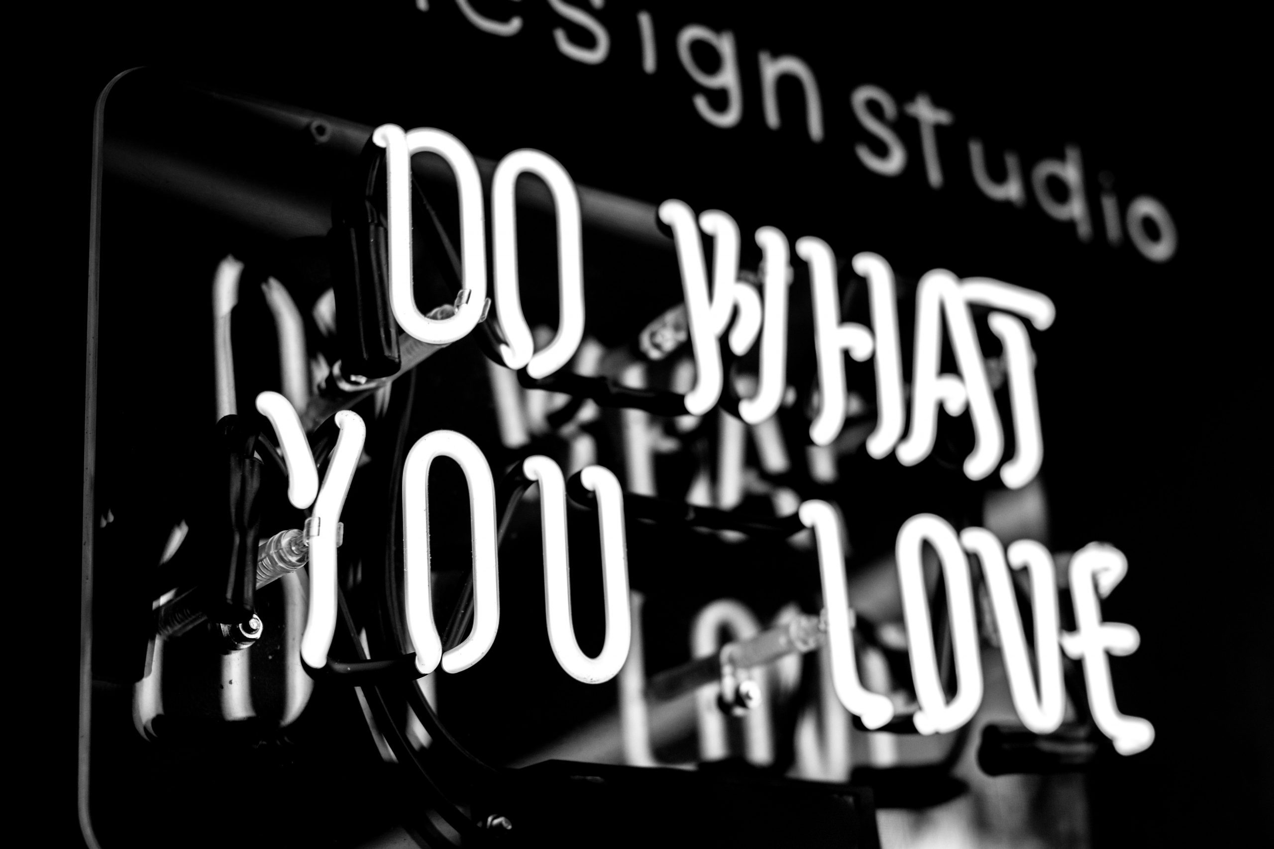 grayscale photo of a neon sign that reads "Do what you love"