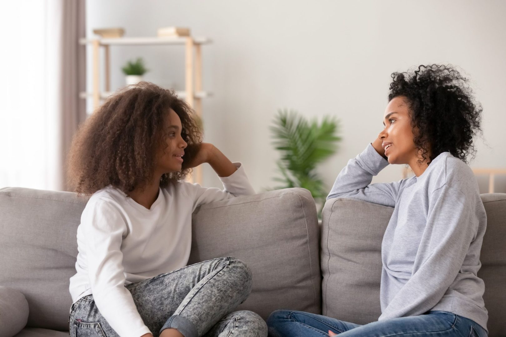 young mom listening teen daughter sitting on couch together